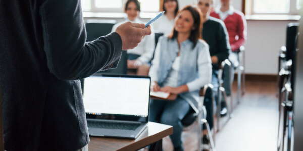 Everyone is smiling and listens. Group of people at business conference in modern classroom at daytime.